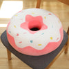 A pink and white plush pillow shaped like a frosted doughnut with colorful sprinkles.