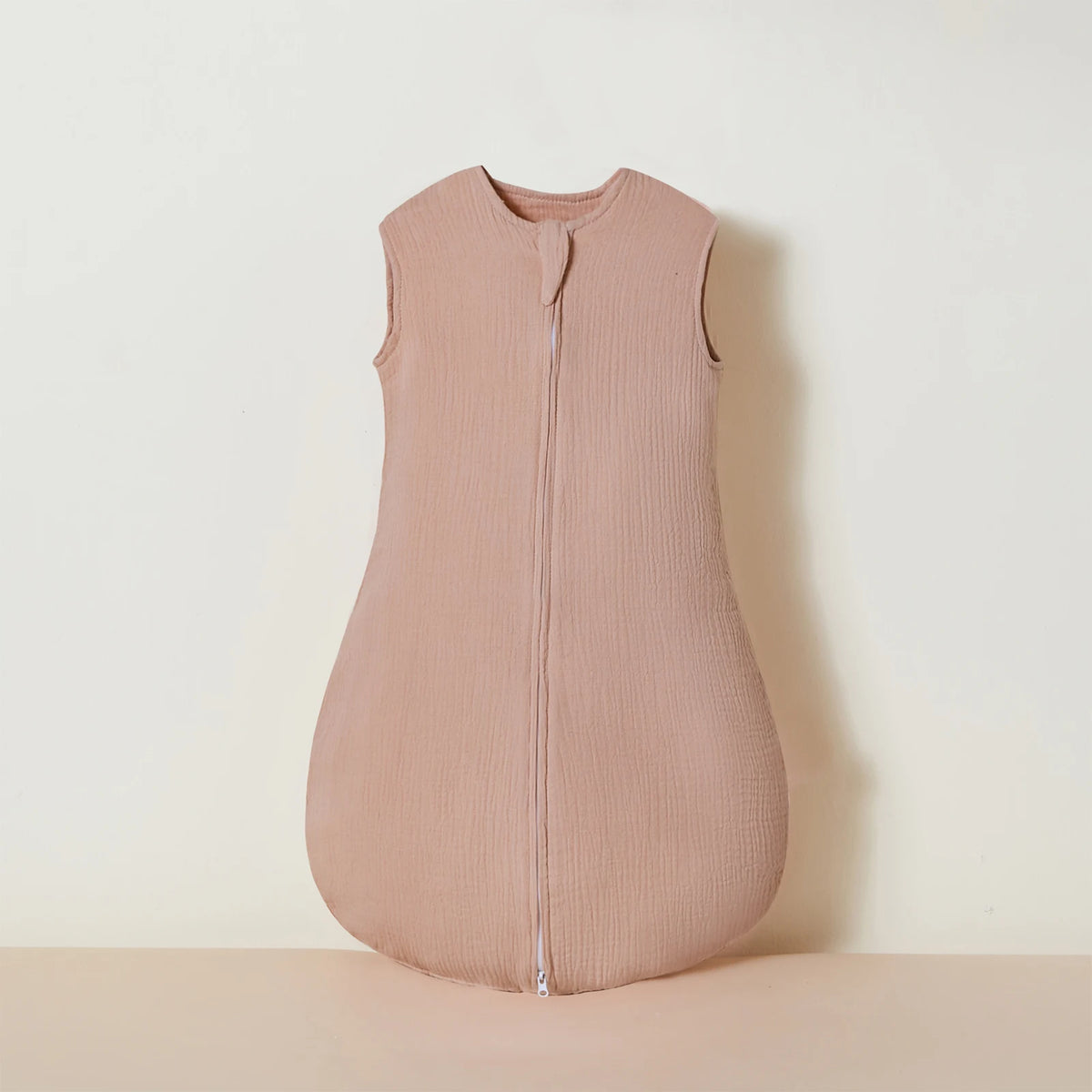A light beige muslin cotton baby sleeping bag displayed on a neutral surface.
