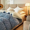 A cozy fleece blanket in blue and white is displayed on a bed with neutral bedding and modern decor.