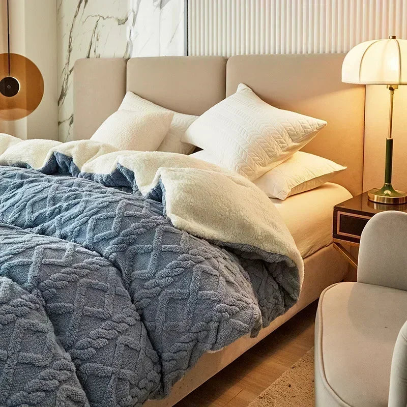 A cozy fleece blanket in blue and white is displayed on a bed with neutral bedding and modern decor.
