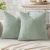 A pair of sage green chenille pillows with a minimalist design resting on a light-colored surface.