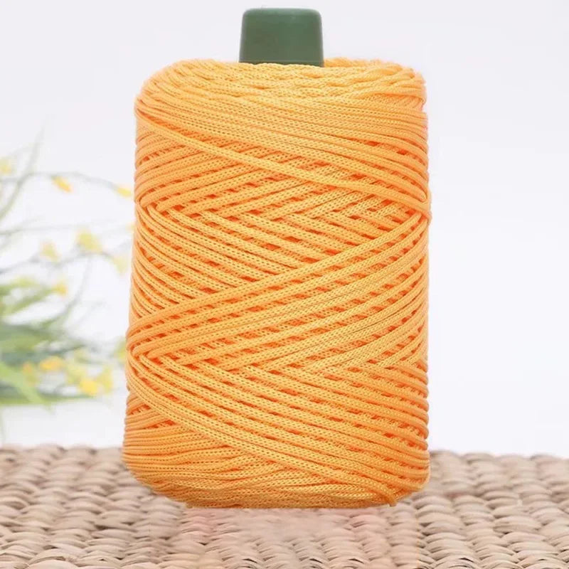 A ball of bright orange 3mm ice rope crochet yarn with a green cap, resting on a woven mat.
