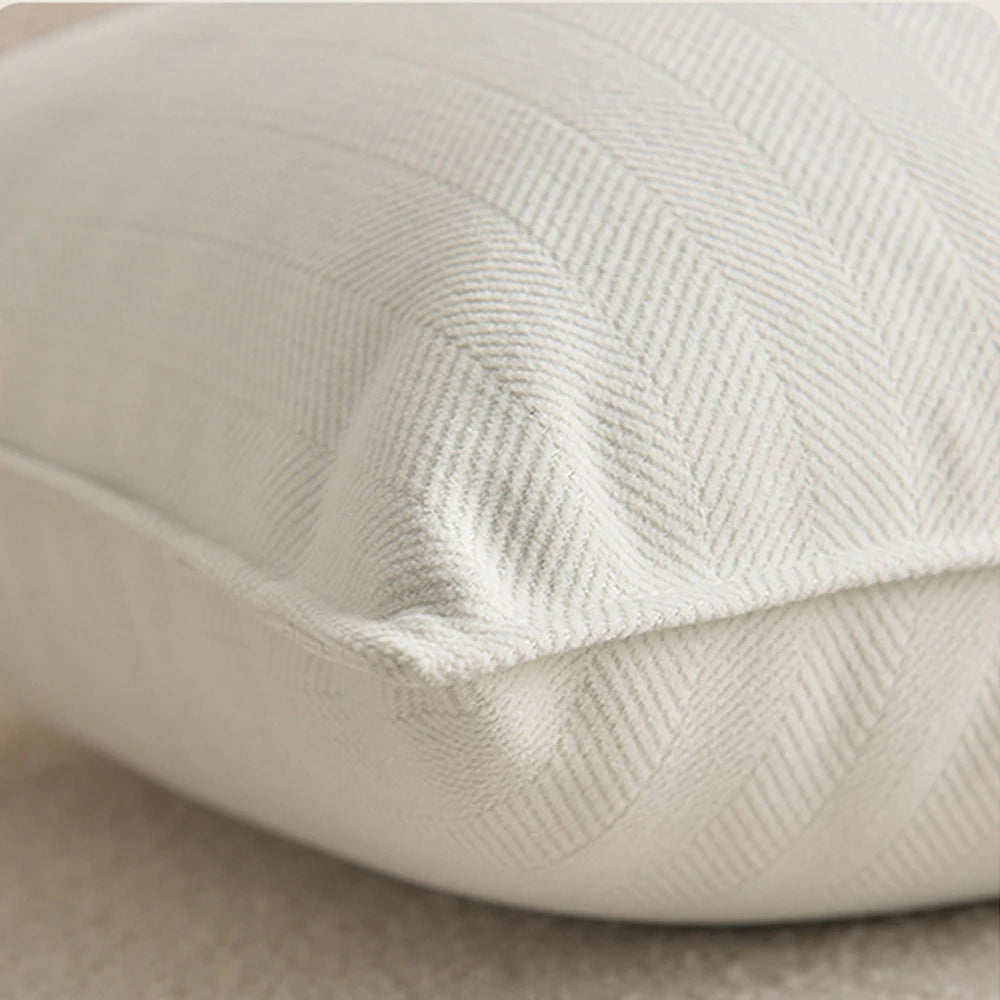 A close-up of a cream-colored luxury chenille throw pillow cover showing its textured fabric detail.