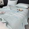 Light blue reversible cooling quilt spread on a bed with pillows and a tray.