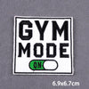 A black and white embroidered patch with the text GYM MODE and an ON switch.