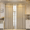 Cream and gold dual-layer blackout curtains with eyelet tops hanging in a light-colored room.