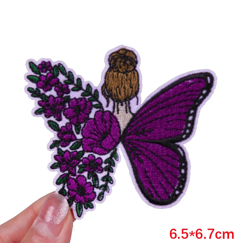 Purple and green embroidered butterfly letter patch on a finger
