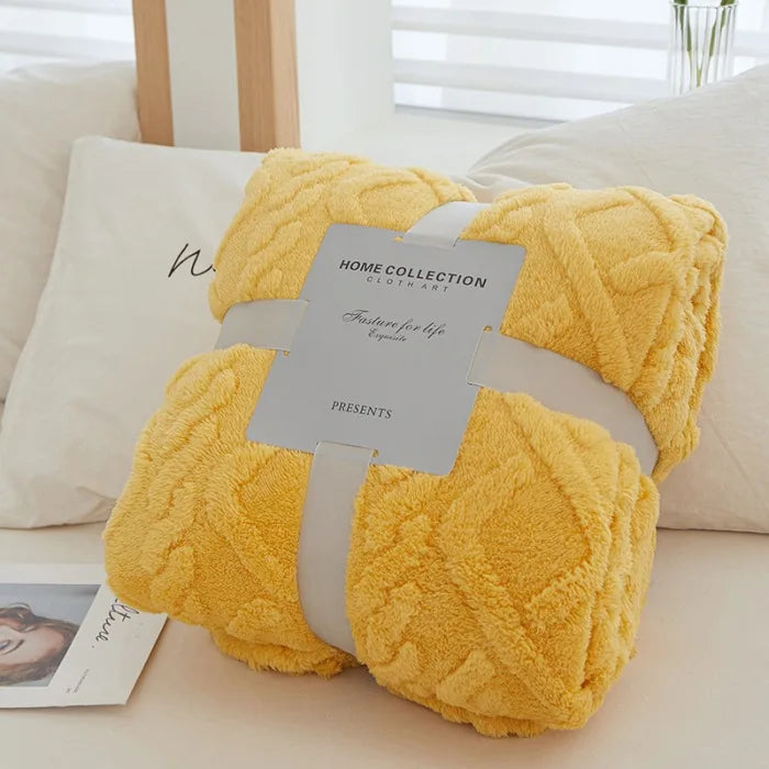 A yellow plush double-sided throw blanket with a textured jacquard pattern resting on a white pillow.