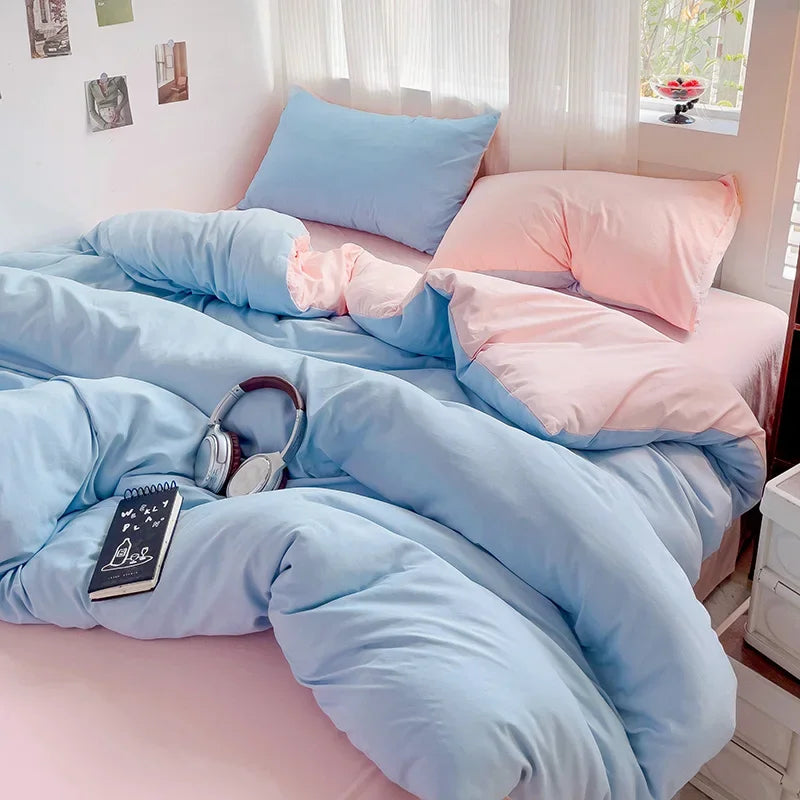 A bed with a light blue duvet and pink pillows, featuring a solid cotton bed linen set.