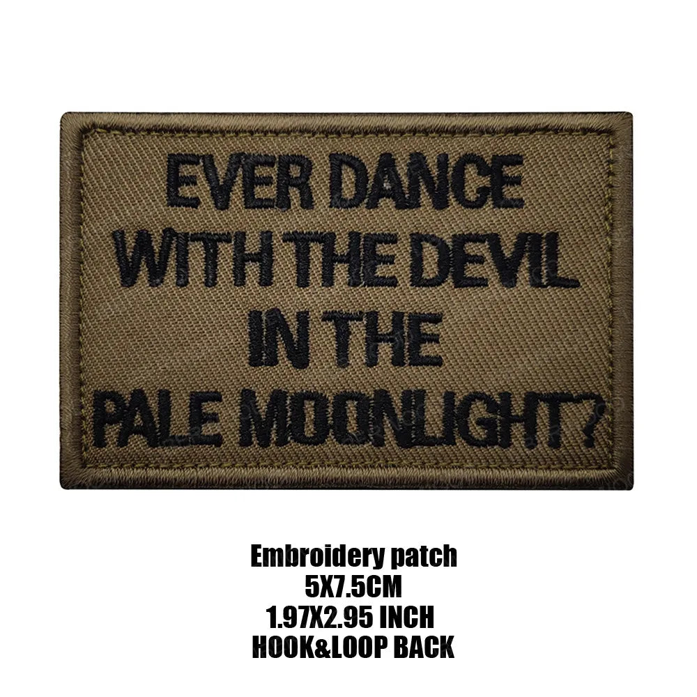 A dark brown embroidered patch with black text that reads Ever Dance With The Devil In The Pale Moonlight