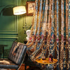Neoclassical sheer curtains with floral embroidery draped in a richly patterned fabric.