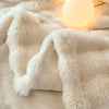 A creamy beige faux fur throw blanket draped over a surface, illuminated by a glowing orb.