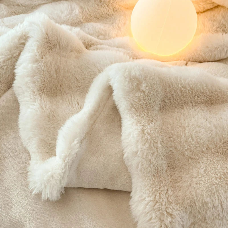 A creamy beige faux fur throw blanket draped over a surface, illuminated by a glowing orb.