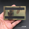 A rectangular tactical patch featuring a national flag design in camouflage colors on a dark background.
