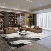 A modern living room featuring a black and white geometric area rug on a polished floor.