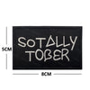 Black embroidered patch with white text that reads SO TALLY TOBER