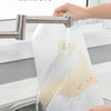A hand is pouring water over a white silicone fridge and drawer liner to demonstrate its washable feature.