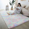 A fluffy pastel pink and blue rug is placed on a light wood floor in a modern living room setting.