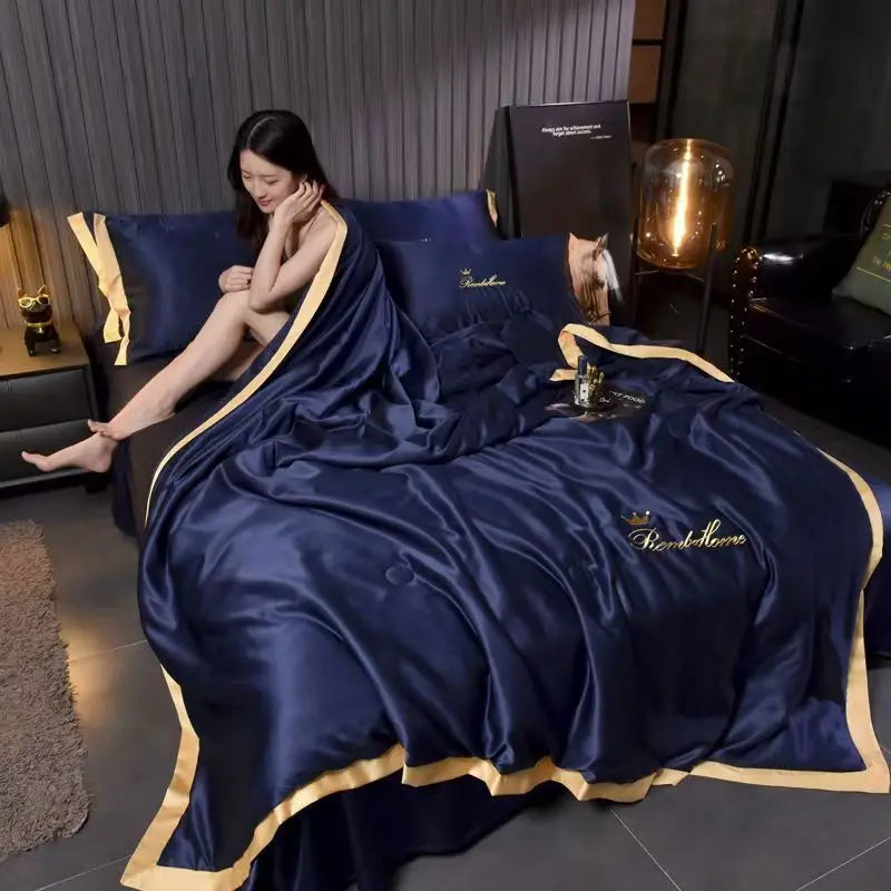 A deep blue luxury ice silk summer blanket set draped on a dark sofa.