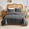 A gray quilted duvet and pillow set displayed on a bed with a wooden headboard.