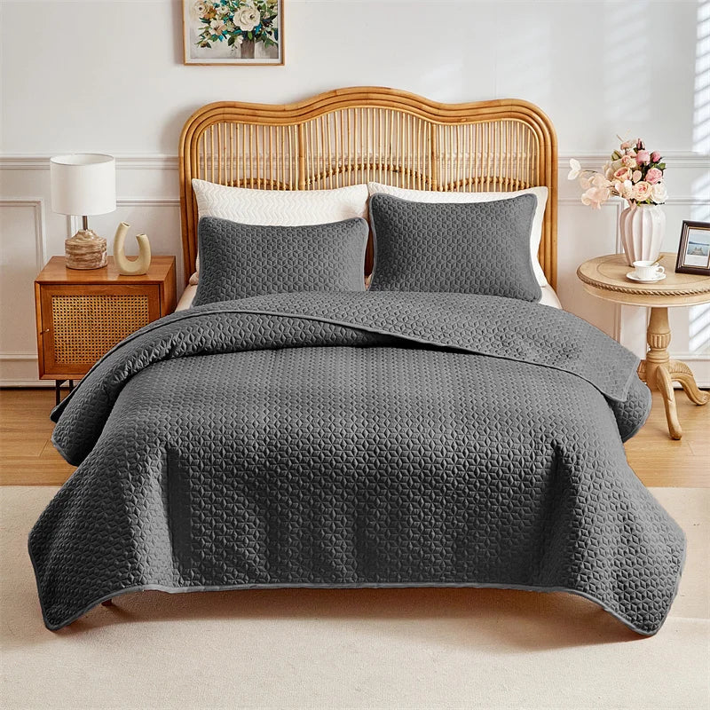 A gray quilted duvet and pillow set displayed on a bed with a wooden headboard.