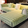 A plush velvet sofa cover in moss green features a quilted texture and non-slip backing.