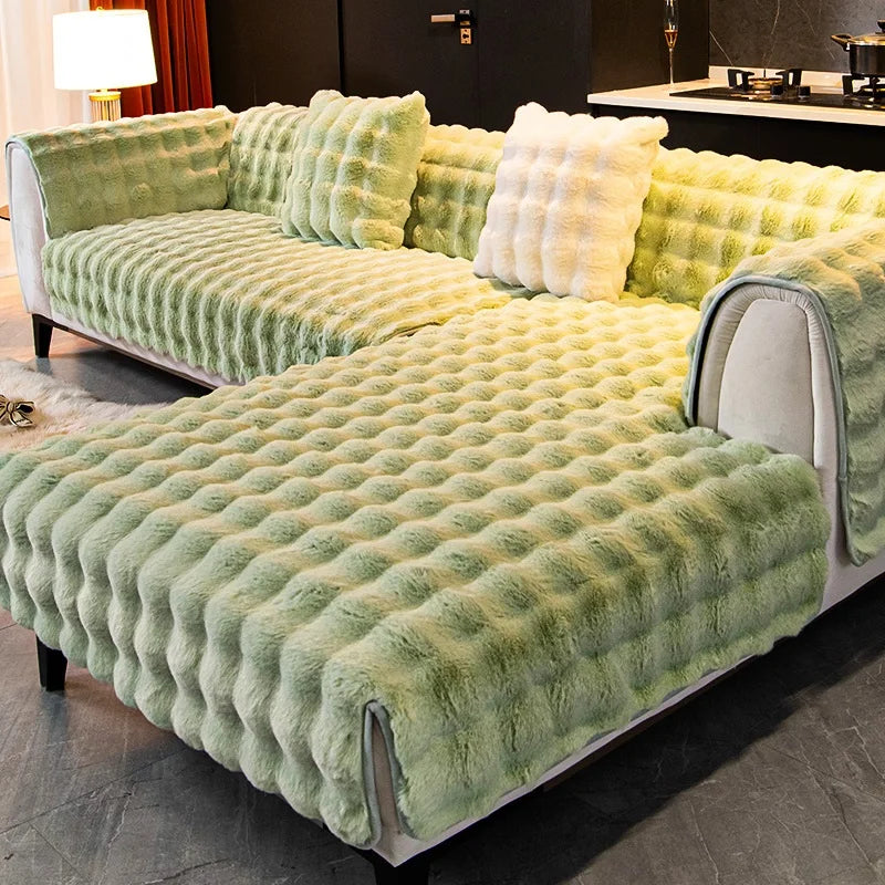 A plush velvet sofa cover in moss green features a quilted texture and non-slip backing.