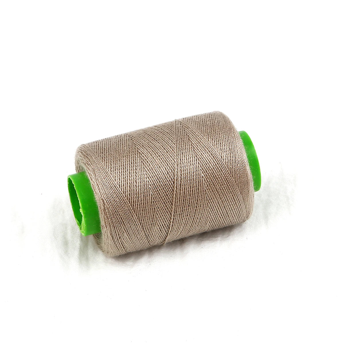 A roll of beige sewing threads with green plastic casing.