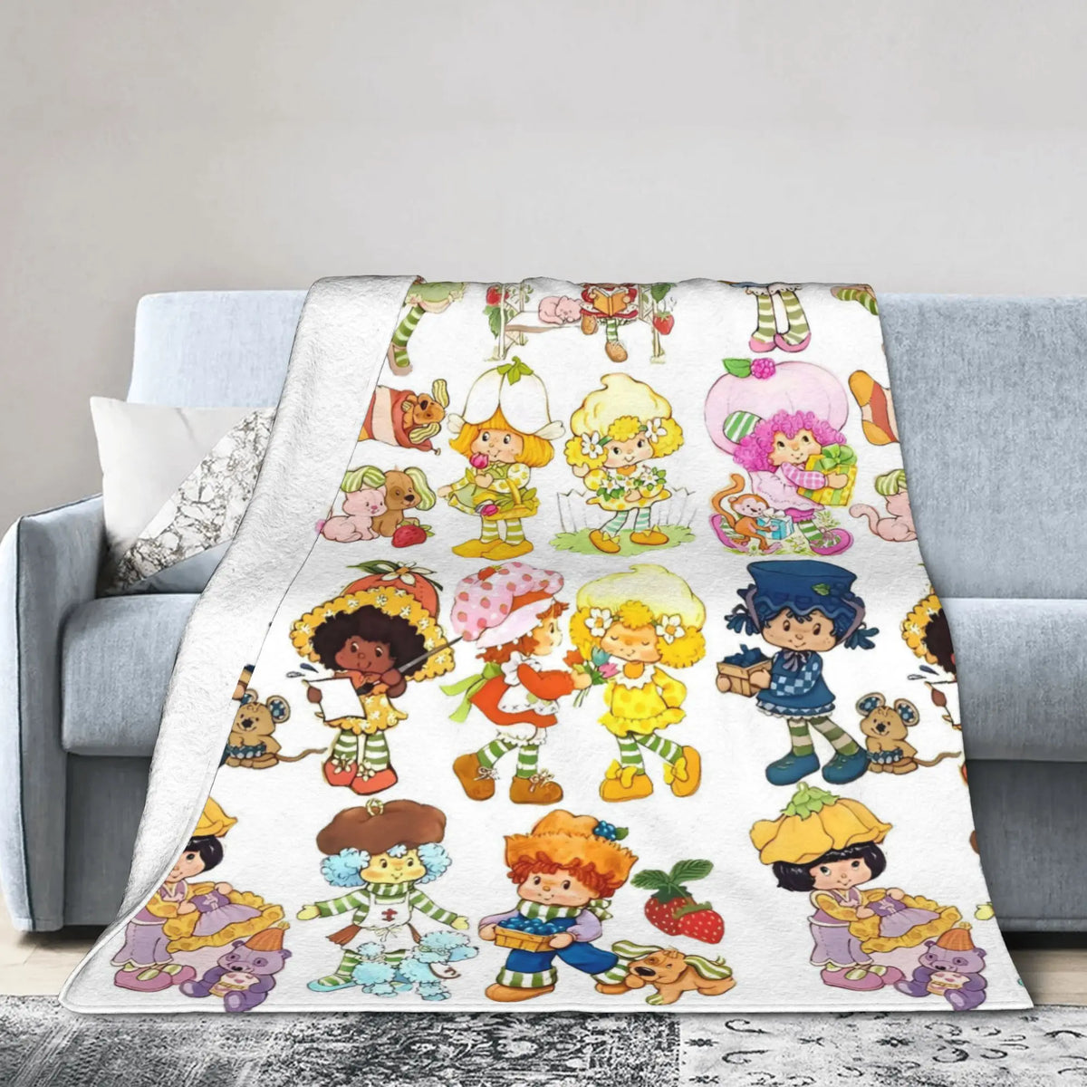 A colorful strawberry shortcake plush throw blanket featuring various sweet characters and fruit designs.