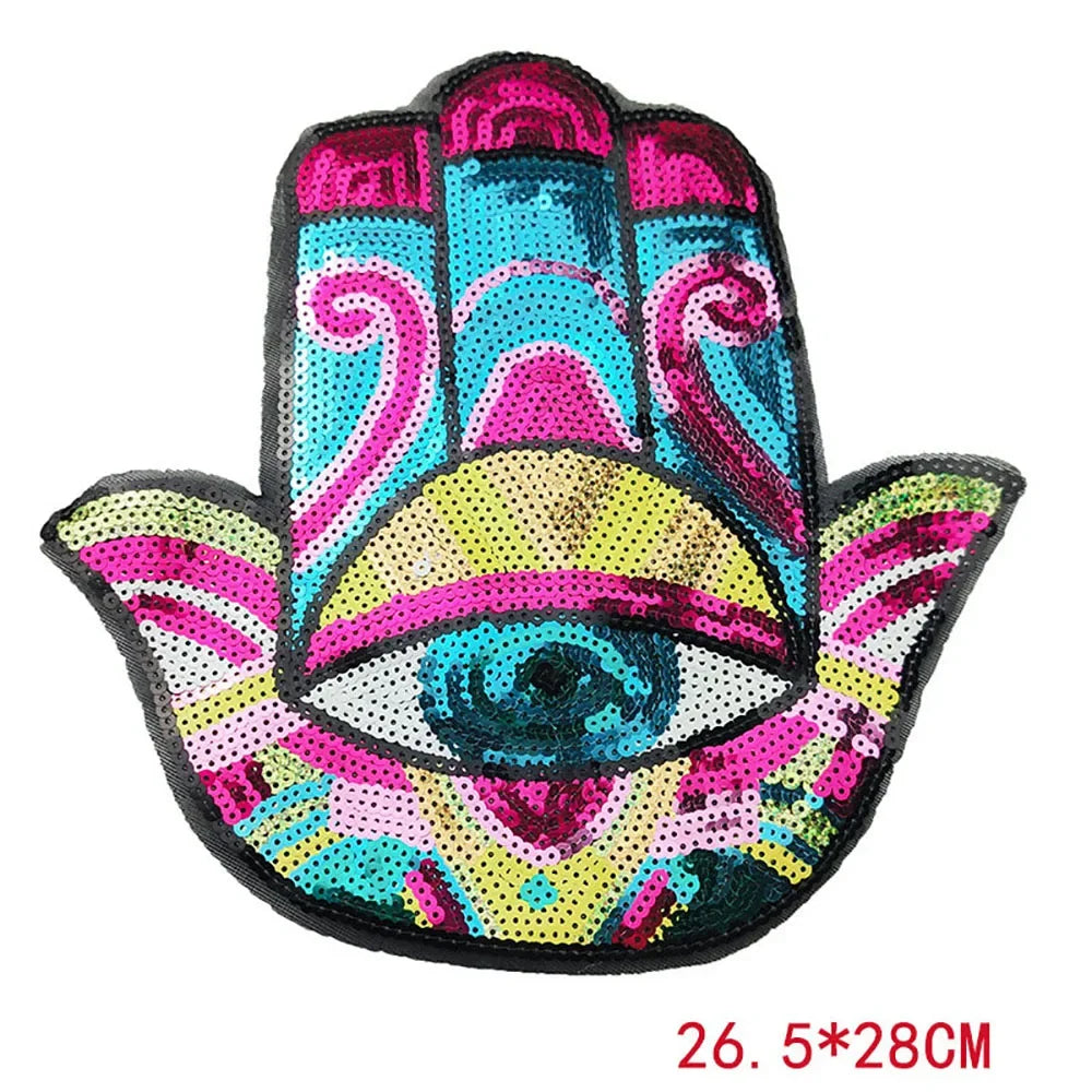 A colorful iron-on patch featuring a stylized blue eye design made of sequins and embroidery.
