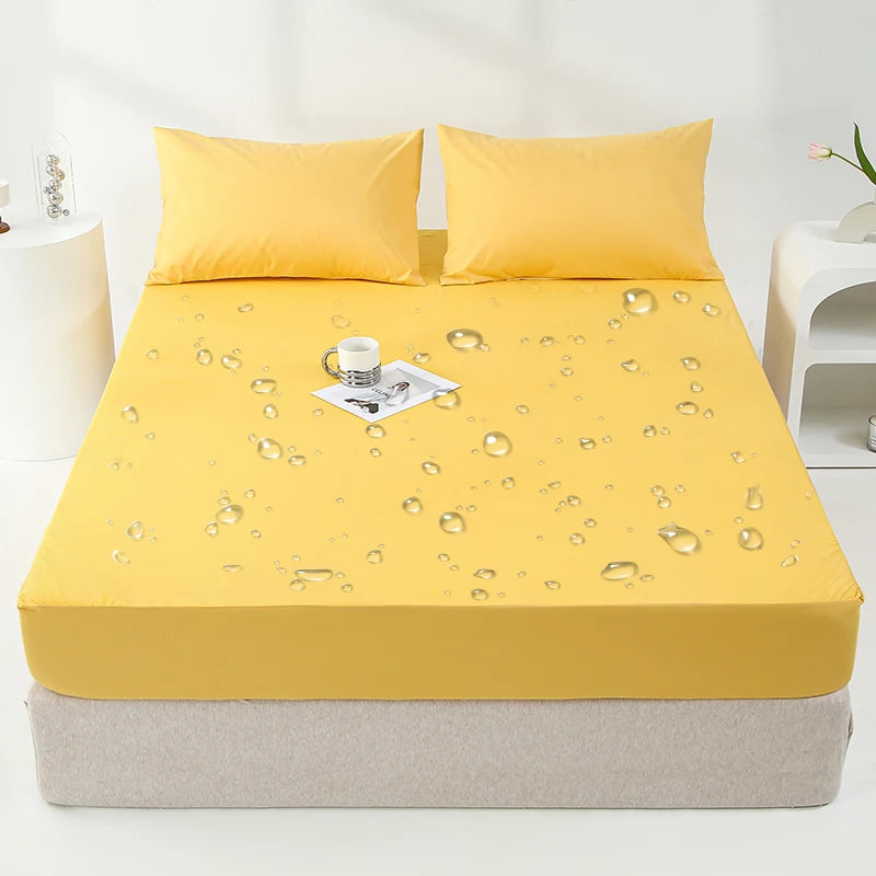 Yellow waterproof mattress and bed protector sheet with pillows and a glass cup on a bed.