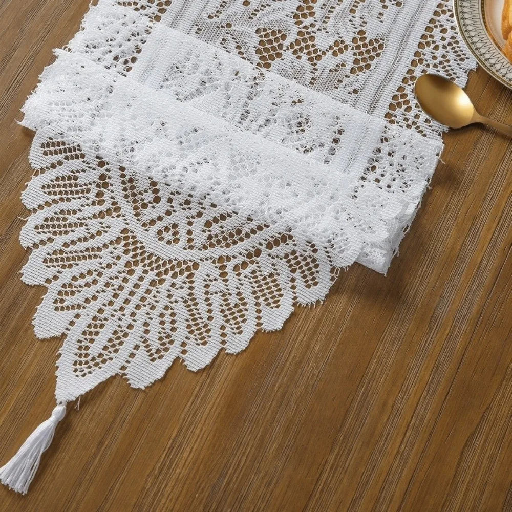 White retro lace table runner with delicate floral pattern and tassels on a wooden surface.