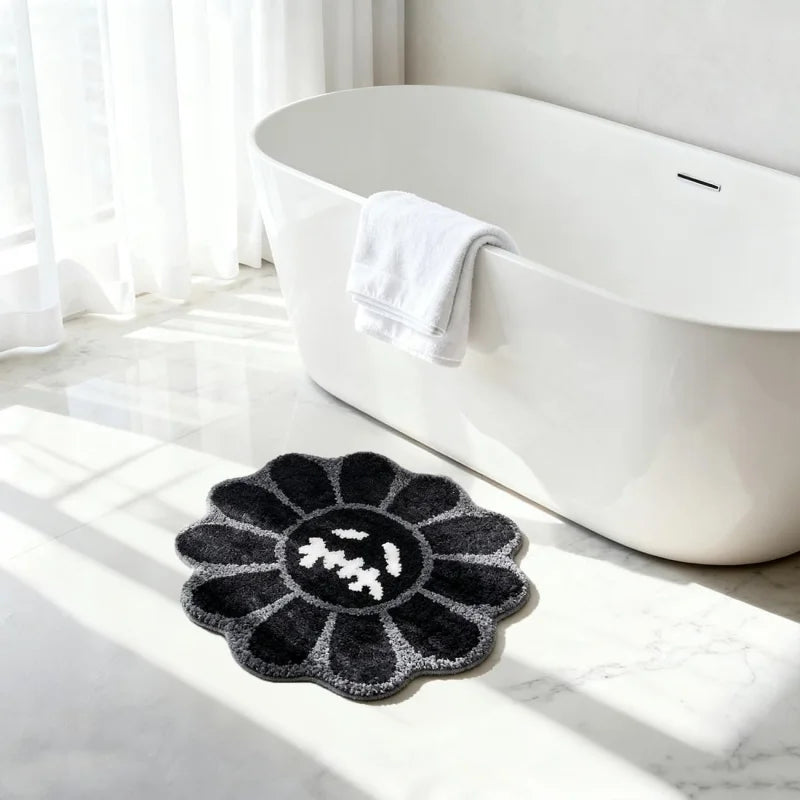 A black gothic sunflower absorbent non-slip bathroom mat placed on a white marble floor next to a white bathtub.