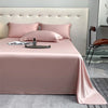 Pink luxury bamboo flat sheets displayed on a bed with pillows and a watch.