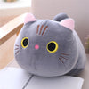 A soft gray cat plush pillow cushion with pink ears and yellow eyes resting on a white surface.