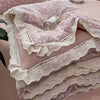 A stack of pink and white floral print quilt blankets with delicate lace trim.