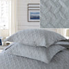 Gray embroidered cotton quilted pillow cover set displayed on a bed with a matching pillow and fabric swatch.