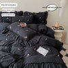 A set of black embroidered rose duvet covers and pillowcases displayed on a bed.