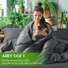 A model is relaxing on a bed covered with a soft gray duvet, demonstrating the airy and gentle feel of the luxury bamboo duve