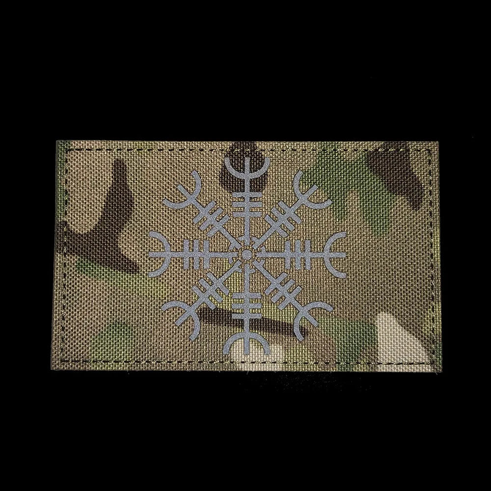 A rectangular embroidered patch featuring a silver Valknut design on a camouflage fabric background.