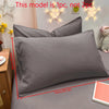 A close-up of a matte gray pillowcase displayed on a bed, with decorative star lights in the background.