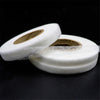 Roll of white double-sided fabric interlining tape on a dark background