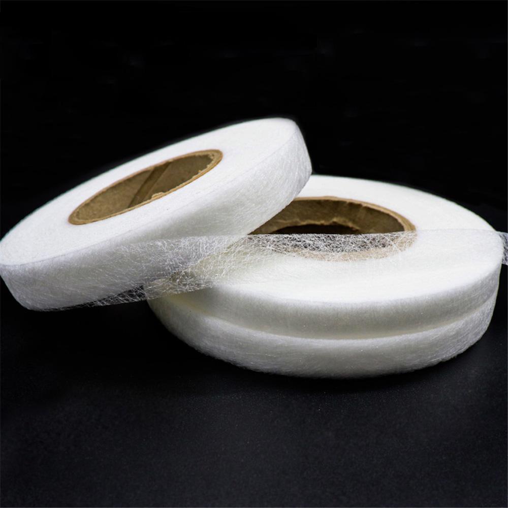 Roll of white double-sided fabric interlining tape on a dark background