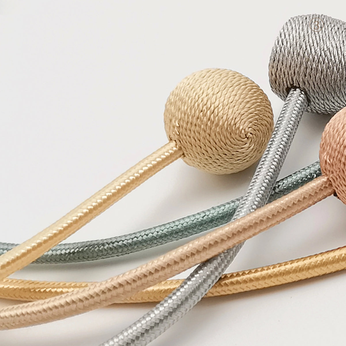 A set of minimalist magnetic ball curtain tiebacks in beige and silver tones.