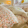 A close-up of a pink floral bedding set featuring various patterned pillows and a duvet on a bed.
