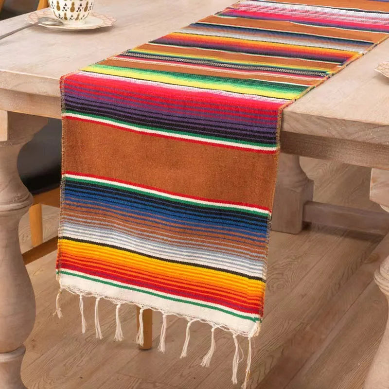 A colorful cotton Mexican sarape table runner with horizontal stripes in orange, green, yellow, and purple colors.