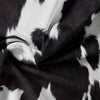 A close-up of a black and white cow print yak leather duvet cover fabric draped in soft folds.