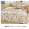 A beige quilted blanket with a floral pattern is displayed on a bed, featuring soft fabric and decorative pillows.