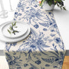 Blue and white porcelain floral linen table runner with delicate botanical patterns on a white tablecloth.