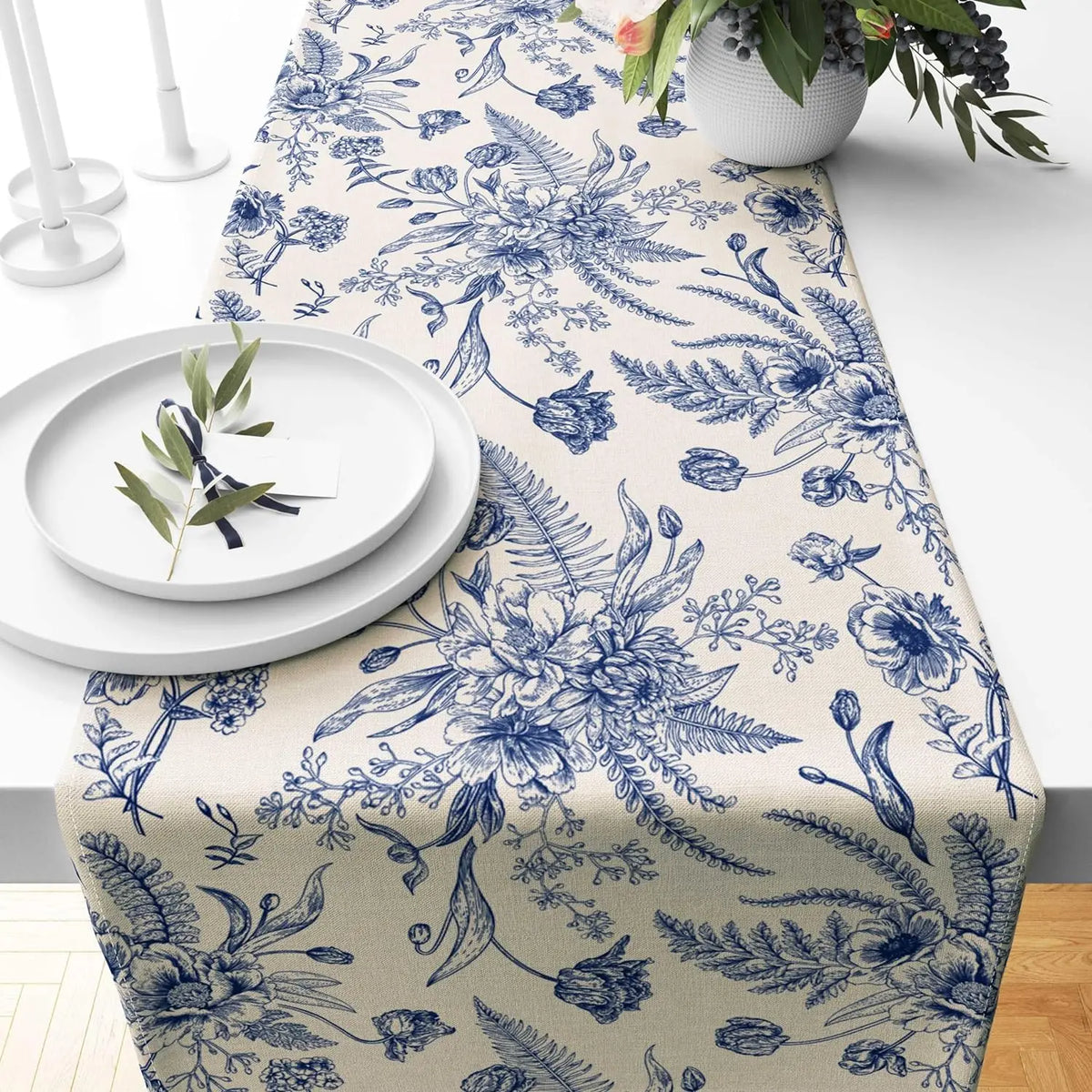 Blue and white porcelain floral linen table runner with delicate botanical patterns on a white tablecloth.